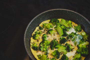 cooking broccoli with eggs in a frying pan