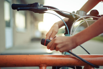 Girl teenager fastening bicycle lock on street parking at sunset