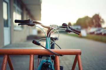 Girl teenager fastening bicycle lock on street parking at sunset