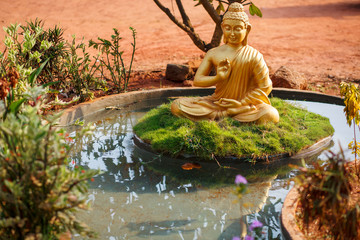 Golden buddha statue by the pond in Goa
