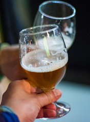 Close-up view of a two glass of beer in hand. Beer glasses clinking in bar or pub