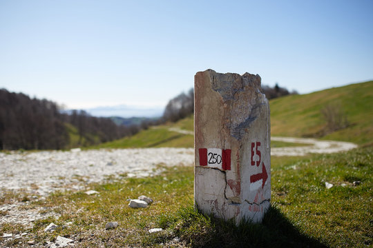 European path E5 with stone cippus and panorama of the mountains in the background
