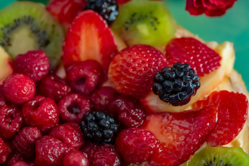 Fruits and berries in sweet gelatin on the cake. Background of strawberries, kiwi, currants, raspberry, pineapple, blackberry. Delicious dessert. Soft focus. Closeup. Top view.