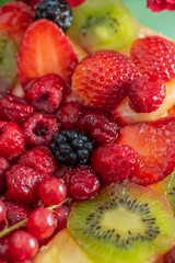 Obraz premium Fruits and berries in sweet gelatin on the cake. Background of strawberries, kiwi, currants, raspberry, pineapple, blackberry. Delicious dessert. Soft focus. Closeup. Top view.