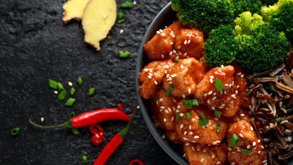 Teriyaki chicken, steamed broccoli and wild rice served in two Asian clay bowls