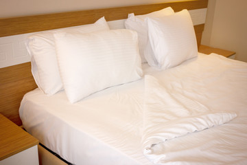 Fototapeta na wymiar Double bed with white linens, prepared for bedtime sleeping