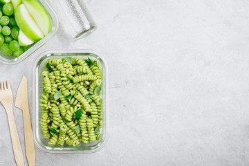 Vegetarian meal prep containers green pesto pasta with basil and pine nuts.  Top view