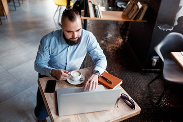 Businessman bearded man in a suit works behind the laptop sitting in a comfortable office coworking.