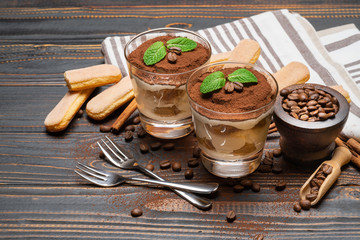 two portions Classic tiramisu dessert in a glass on wooden background