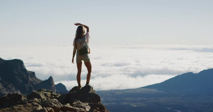 Young adventurous woman standing on the top of a mountain enjoying the view, active summer hiking lifestyle