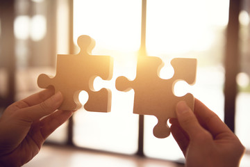 Closeup hand of woman connecting jigsaw puzzle with sunlight effect, Business solutions, success...
