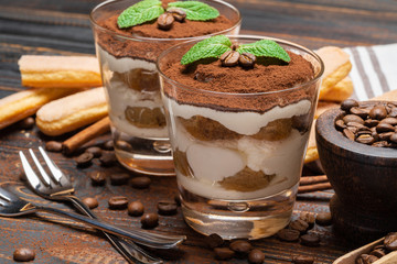 two portions Classic tiramisu dessert in a glass on wooden background