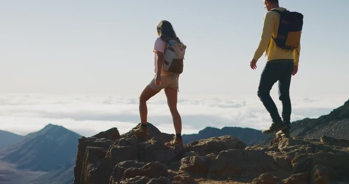 Young adventurous couple hiking together on the top of a mountain in slow motion, summer wilderness excursions