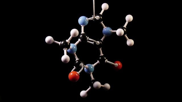 Caffeine C8H10N4O2 molecule rotating on black background