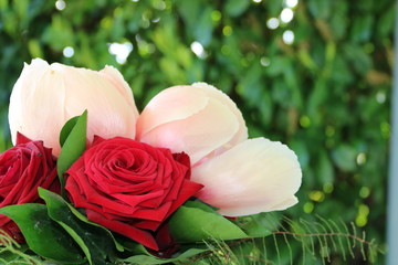Fototapeta premium Blumenstrauss mit roten Rosen und rosa Pfingstrosen vor grünem Hintergrund in der Natur