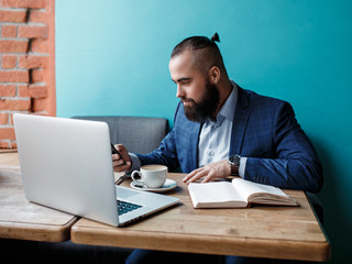 Fototapeta premium Businessman bearded man in a suit works behind the laptop sitting in a comfortable office coworking.