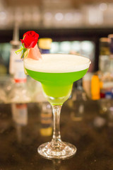 Green alcoholic cocktail with mint in a margarita glass on a bar counter
