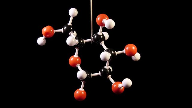 Glucose C6H12O6 molecule rotating on black background