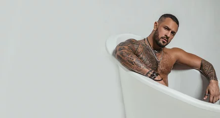 Gartenposter spa and hygiene. time to relax in bathroom. confidence charisma. brutal sportsman. steroids. muscular man with athletic body. sexy abs of tattoo man in bath tub. stay clean and fresh. copy space © Volodymyr