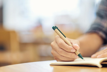 Close-up of businessman hand with pen writing on notebook. Business and education concept.
