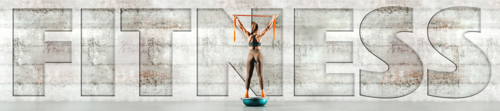 Full length of sporty woman standing on bosu ball and holding ribbon. Back turned, in background gray wall. Upper-case fitness over the picture.
