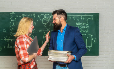 Bearded tutor helping his student. Teacher couple. Teacher helping his students with math or...
