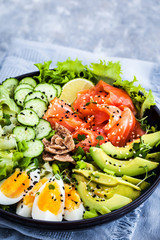 Salmon poke bowl served with avocado, eggs, cucumber and greens