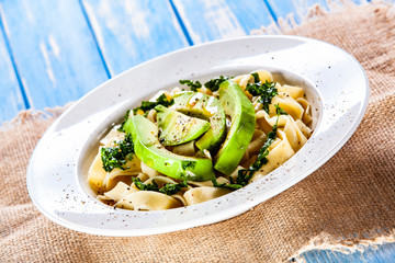 Pasta with avocado on wooden table