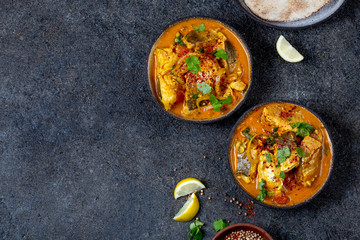 INDIAN FOOD. Traditional KERALA FISH CURRY with naan bread, gray plate, black background 