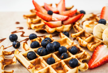 Fresh homemade waffles decorated with blueberries, strawberries and bananas