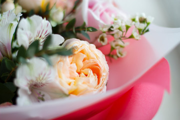 yellow-orange large delicate flower surrounded by small white and pink flowers in a bouquet
