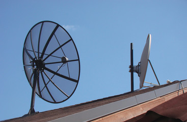 Two satellite dishes on the roof. Frame black antenna and white antenna. The concept of reception and transmission of data.