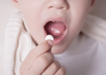 The child puts the pill into his mouth. Close-up Photos