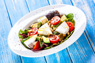 Salad with avocado and cheese on wooden background