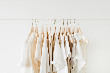 Minimal fashion clothes concept. White female blouses and t-shirts on hanger on white background.