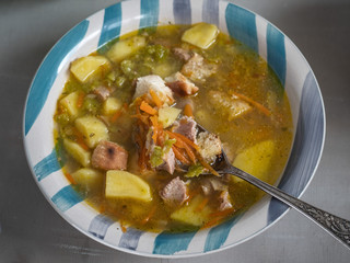 Pea soup in a deep striped ceramic plate with crackers shot close-up.