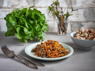 A light snack of lentils with roasted carrots and onions, crackers and salad on belos table.