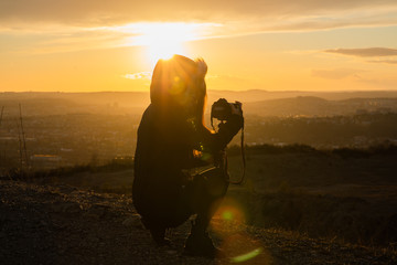 Girl taking photos during colored sunset in quarry Hady Brno with view inside city