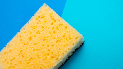 Yellow kitchen sponge on blue background. House cleaning. Household. Cope space.