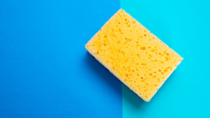 Yellow kitchen sponge on blue background. House cleaning. Household. Cope space.