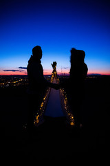 Obraz premium Girl taking photos during colored sunset in quarry Hady Brno with view inside city