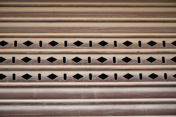 A rhomboid structure in the middle of an old, rusty garage door in Spain.
