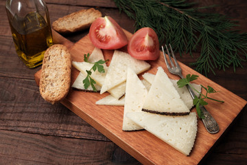 Rustic table of sliced ewe's cheese with pieces of tomato