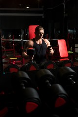 Fototapeta na wymiar Muscular male using smartphone in gym