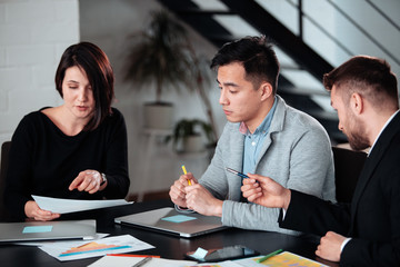 Making great decisions. Young beautiful man woman discussing something with smile while her coworkers listening to her sitting at the office table, group team young freelancers