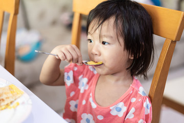 Asian little baby child eating and enjoy breakfast by herself