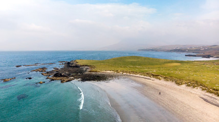 Vue a&eacute;rienne sur une plage de sable blanc, eau turquoise et prairie verte