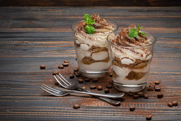 two portions Classic tiramisu dessert in a glass on wooden background