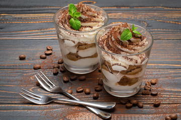two portions Classic tiramisu dessert in a glass on wooden background
