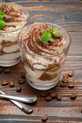two portions Classic tiramisu dessert in a glass on wooden background